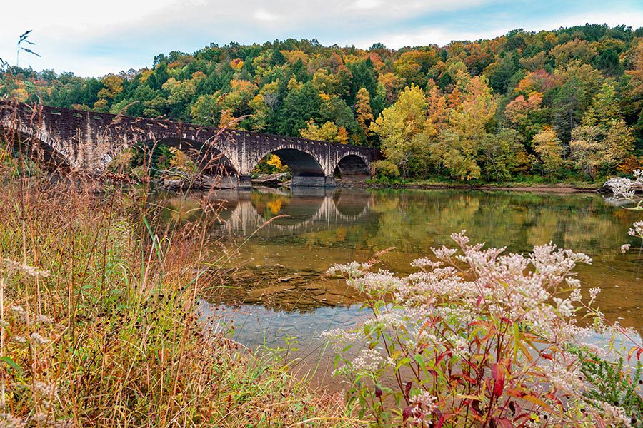 About Our Agency - Stone Arched Gatliff Bridge in Kentucky in Autumn, Trees Turning Beautiful Colors